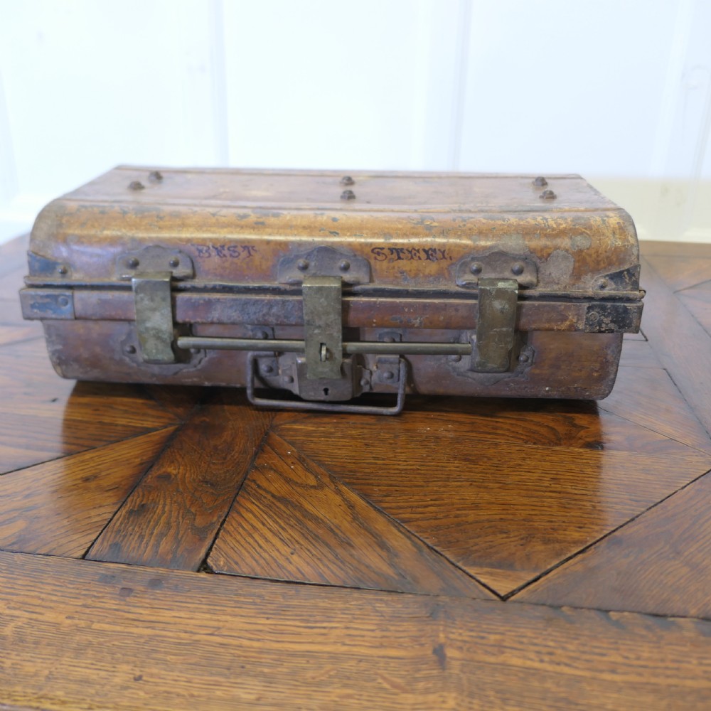 An antique patinated steel travel trunk featuring riveted metal edges, brass latches, and stencilled lettering reading Best Steel.