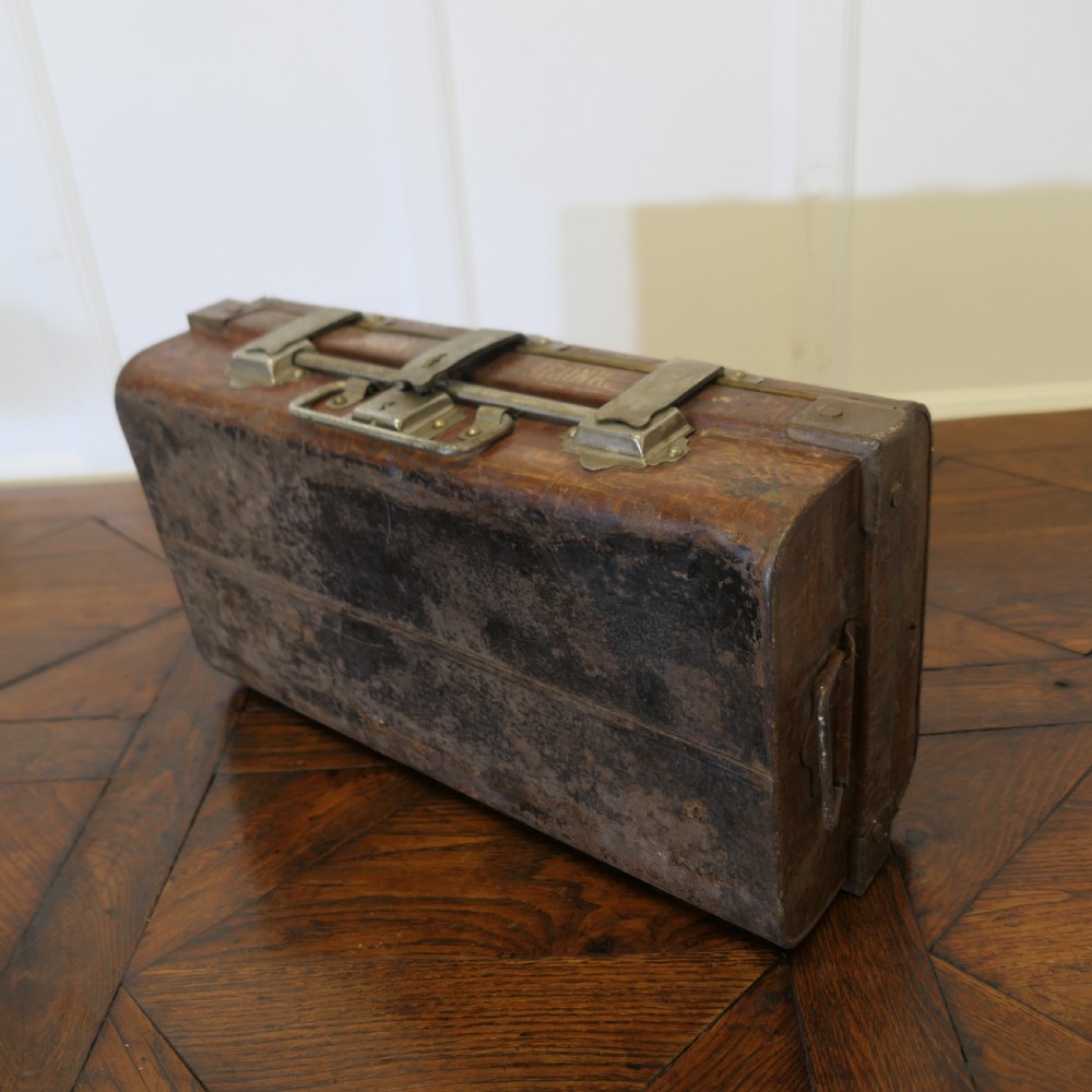 A small dark brown steel cabin trunk featuring three front metal latches, a central folding handle, and painted lettering reading Best Steel Cabin Trunk. View III