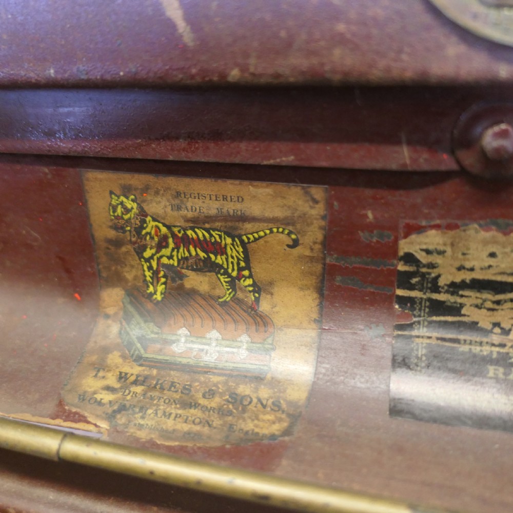 A small dark brown steel cabin trunk featuring three front metal latches, a central folding handle, and painted lettering reading Best Steel Cabin Trunk. View V