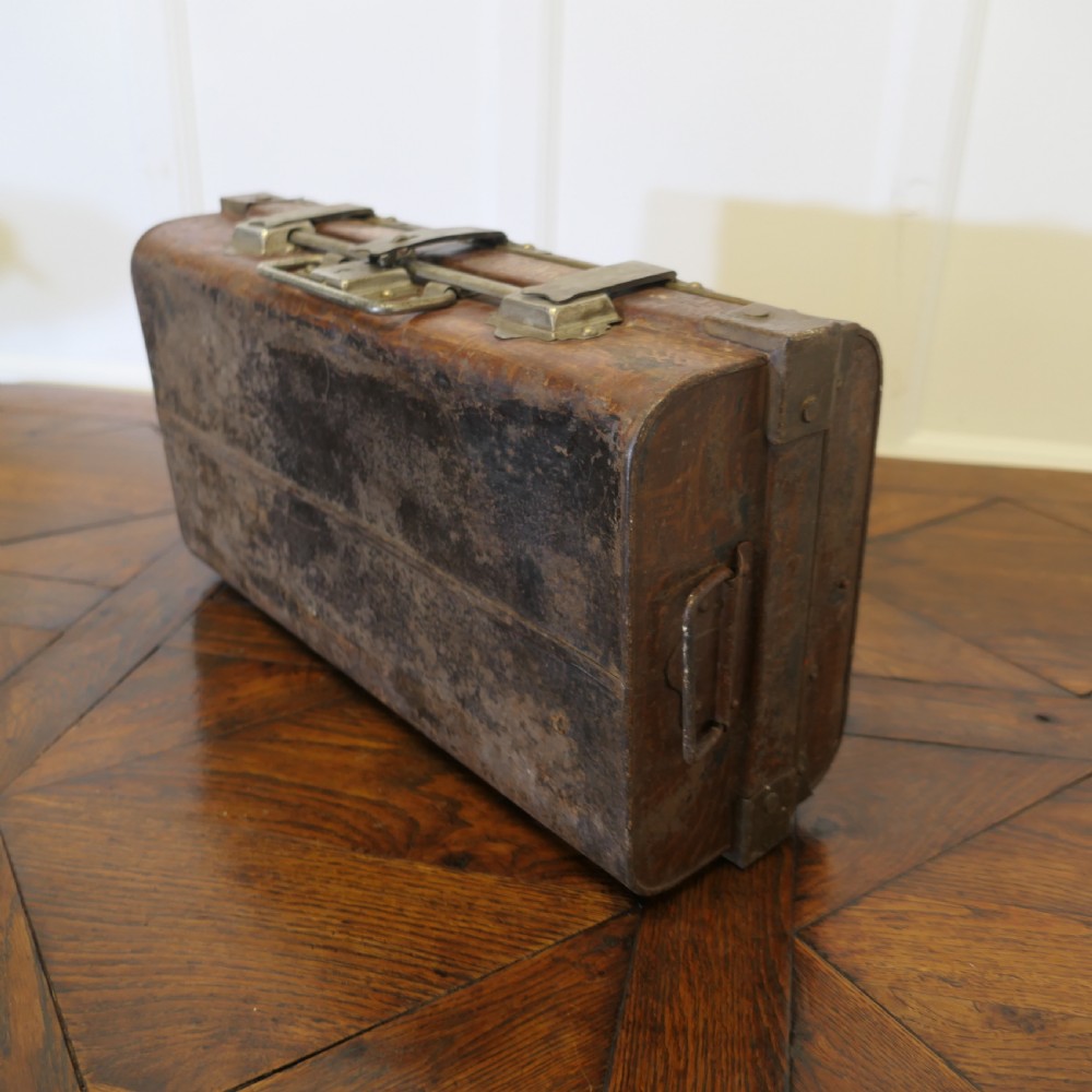 A small dark brown steel cabin trunk featuring three front metal latches, a central folding handle, and painted lettering reading Best Steel Cabin Trunk. View IX