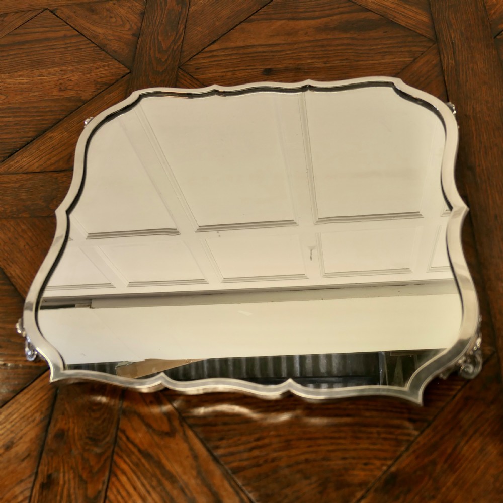 A French Art Deco silver-plated tray featuring a shaped mirror base with scalloped edges and cast scroll feet. View V