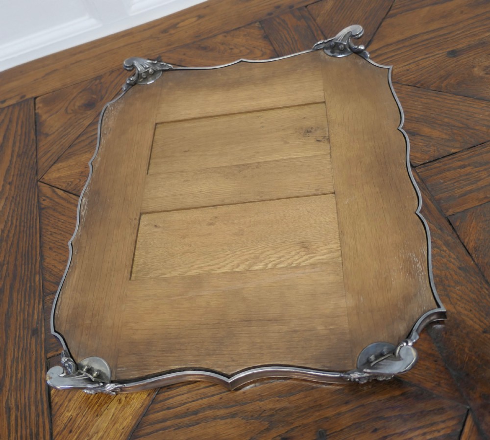 A French Art Deco silver-plated tray featuring a shaped mirror base with scalloped edges and cast scroll feet. View VII