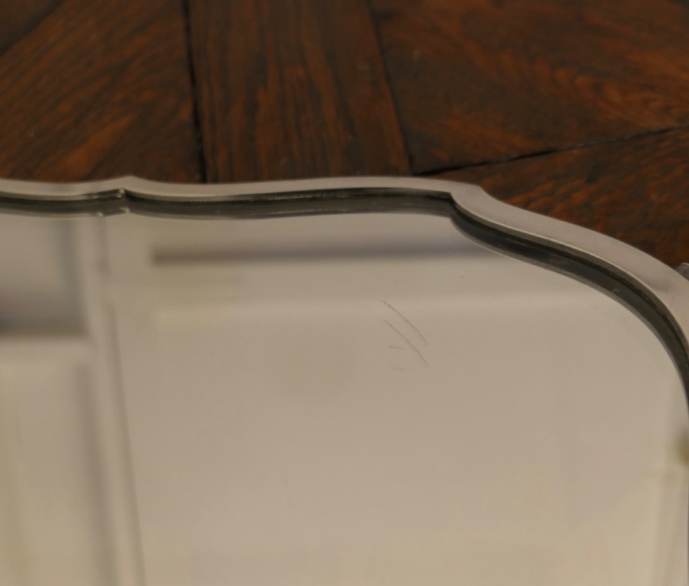 A French Art Deco silver-plated tray featuring a shaped mirror base with scalloped edges and cast scroll feet. View VIII