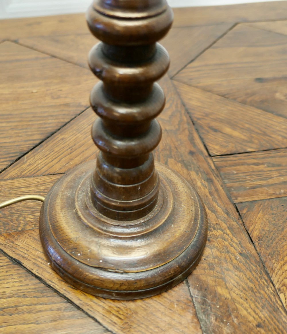 A tall turned dark oak table lamp with a carved baluster column base and a cream fabric shade. View VI