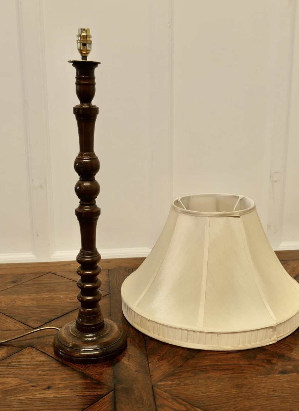 A tall turned dark oak table lamp with a carved baluster column base and a cream fabric shade. View VIII