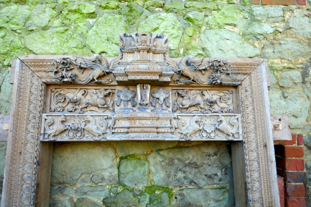 An intricately carved natural teak wooden archway featuring relief carvings of elephants and architectural motifs. View IV