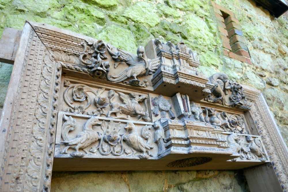 An intricately carved natural teak wooden archway featuring relief carvings of elephants and architectural motifs. View VIII