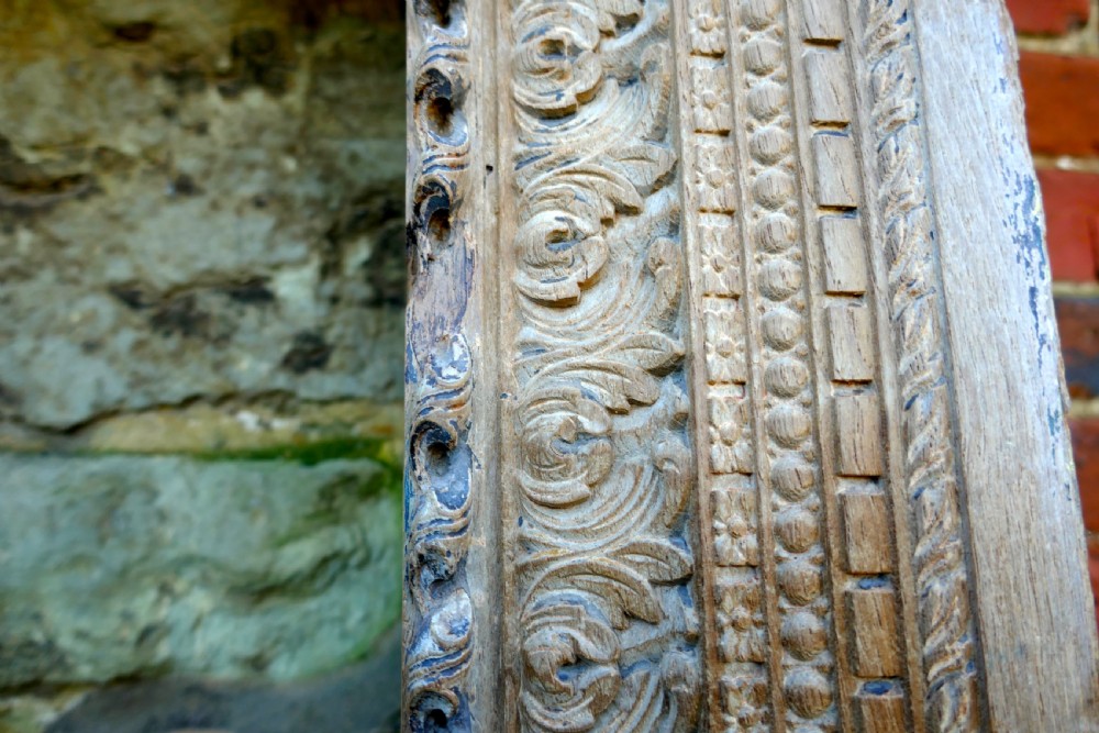 An intricately carved natural teak wooden archway featuring relief carvings of elephants and architectural motifs. View IX