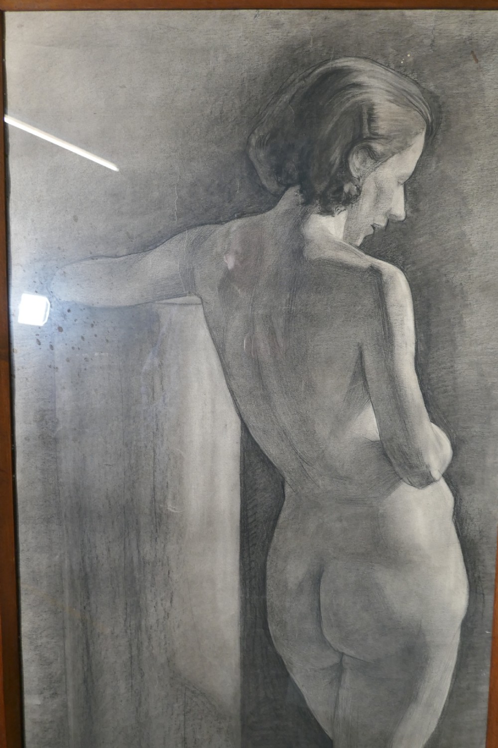 A full-length charcoal study of a standing female nude in profile and back view, set within a polished timber frame. View II