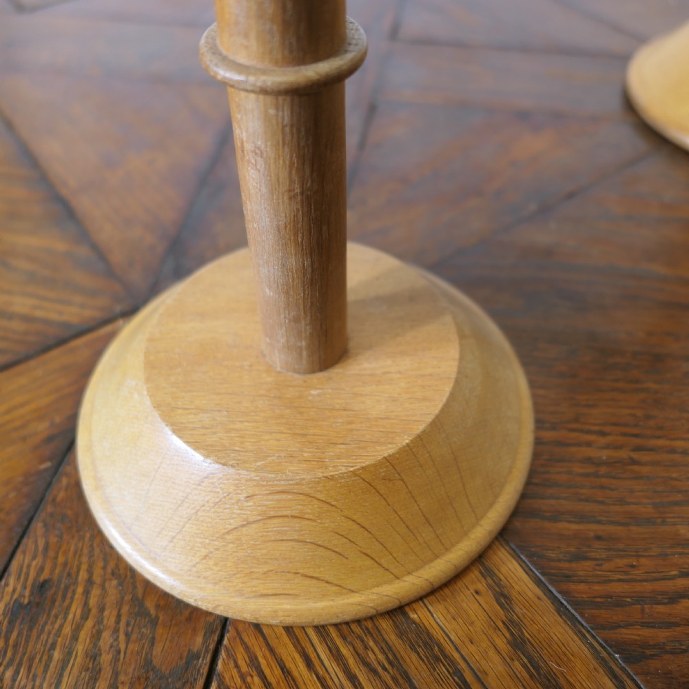 A pair of turned golden oak hat stands featuring circular weighted bases and woven fabric upholstered dome tops. View VI