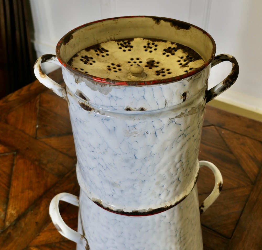A tall antique white and blue marbled enamel coffee urn featuring a brass tap near the base, loop side handles, and red trim along the rim. View VI