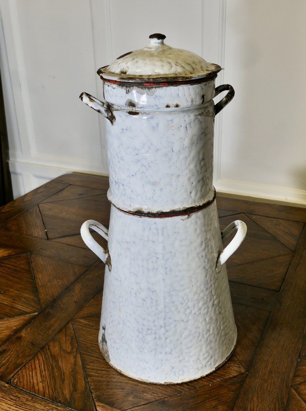 A tall antique white and blue marbled enamel coffee urn featuring a brass tap near the base, loop side handles, and red trim along the rim. View VIII