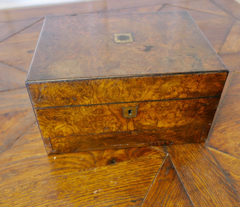 A set of three polished antique burr walnut storage boxes featuring brass keyhole escutcheons resting on a parquet floor. View II
