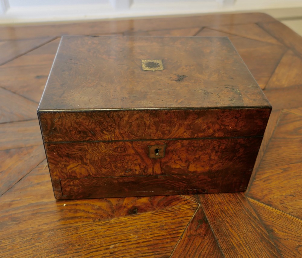 A set of three polished antique burr walnut storage boxes featuring brass keyhole escutcheons resting on a parquet floor. View III