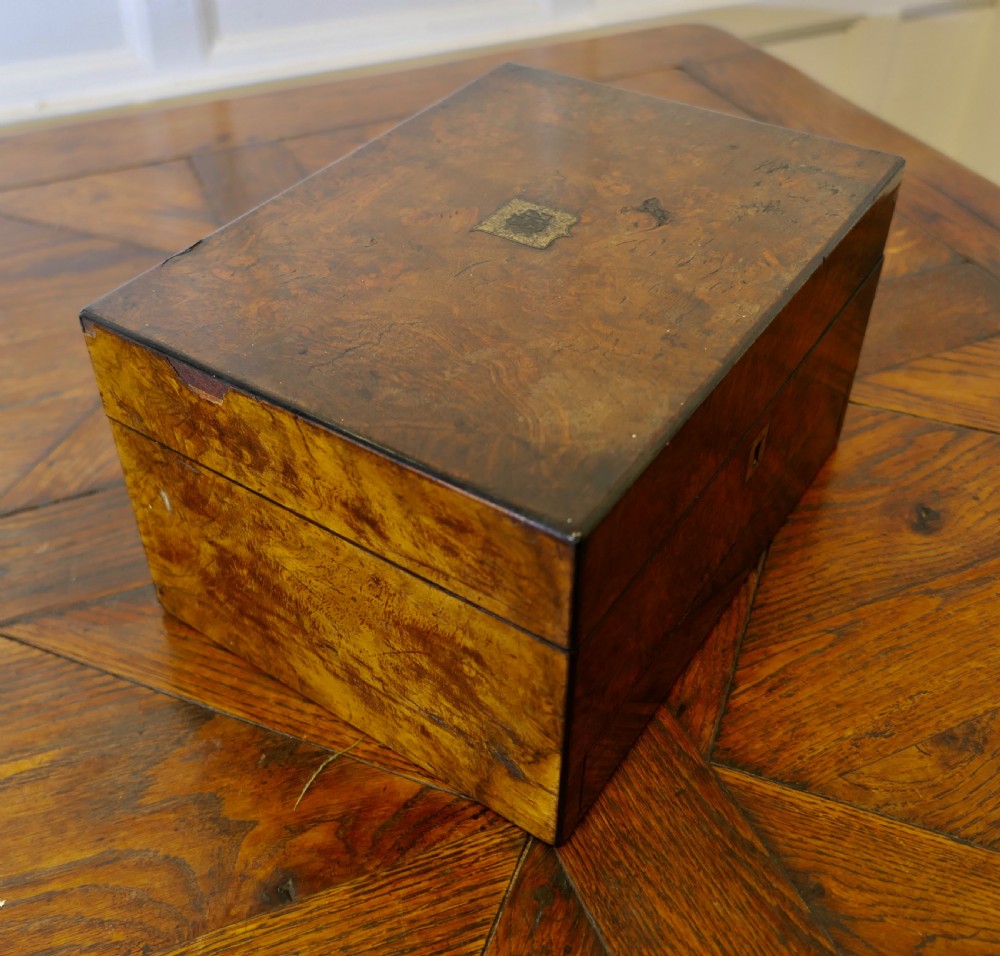 A set of three polished antique burr walnut storage boxes featuring brass keyhole escutcheons resting on a parquet floor. View IV