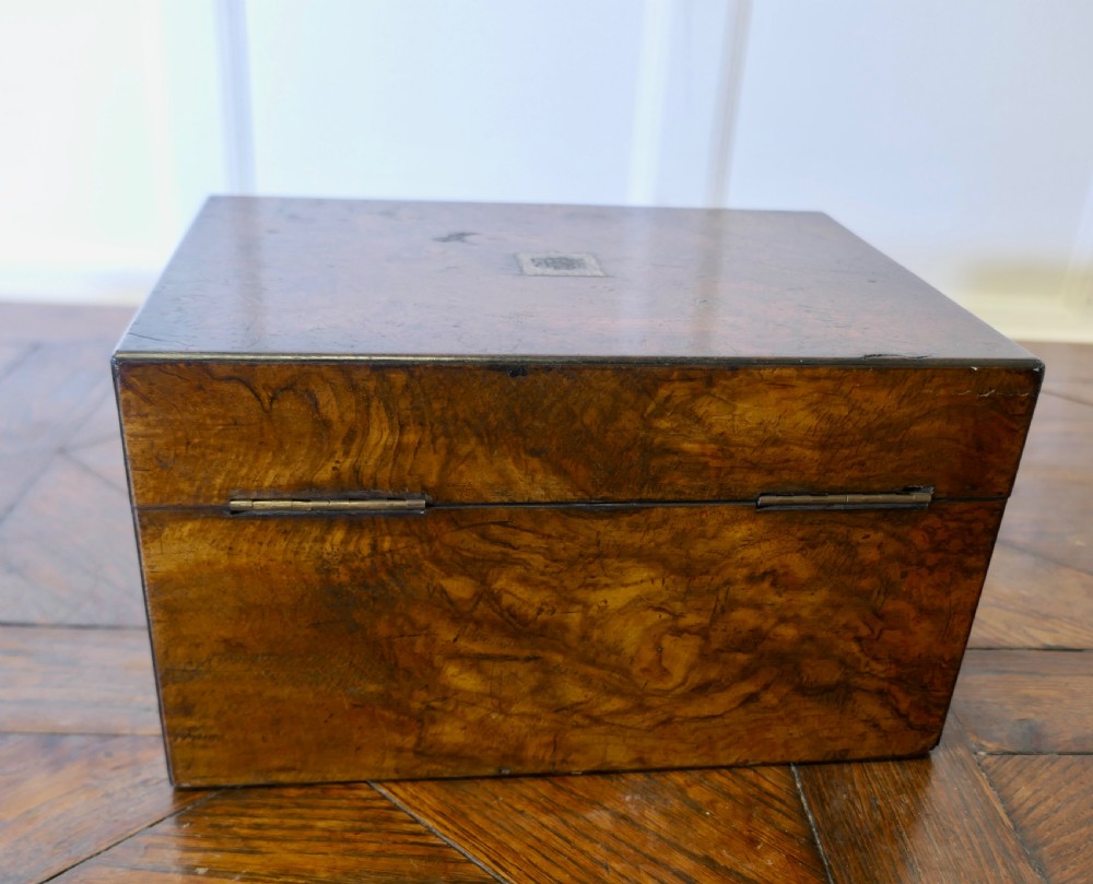 A set of three polished antique burr walnut storage boxes featuring brass keyhole escutcheons resting on a parquet floor. View V
