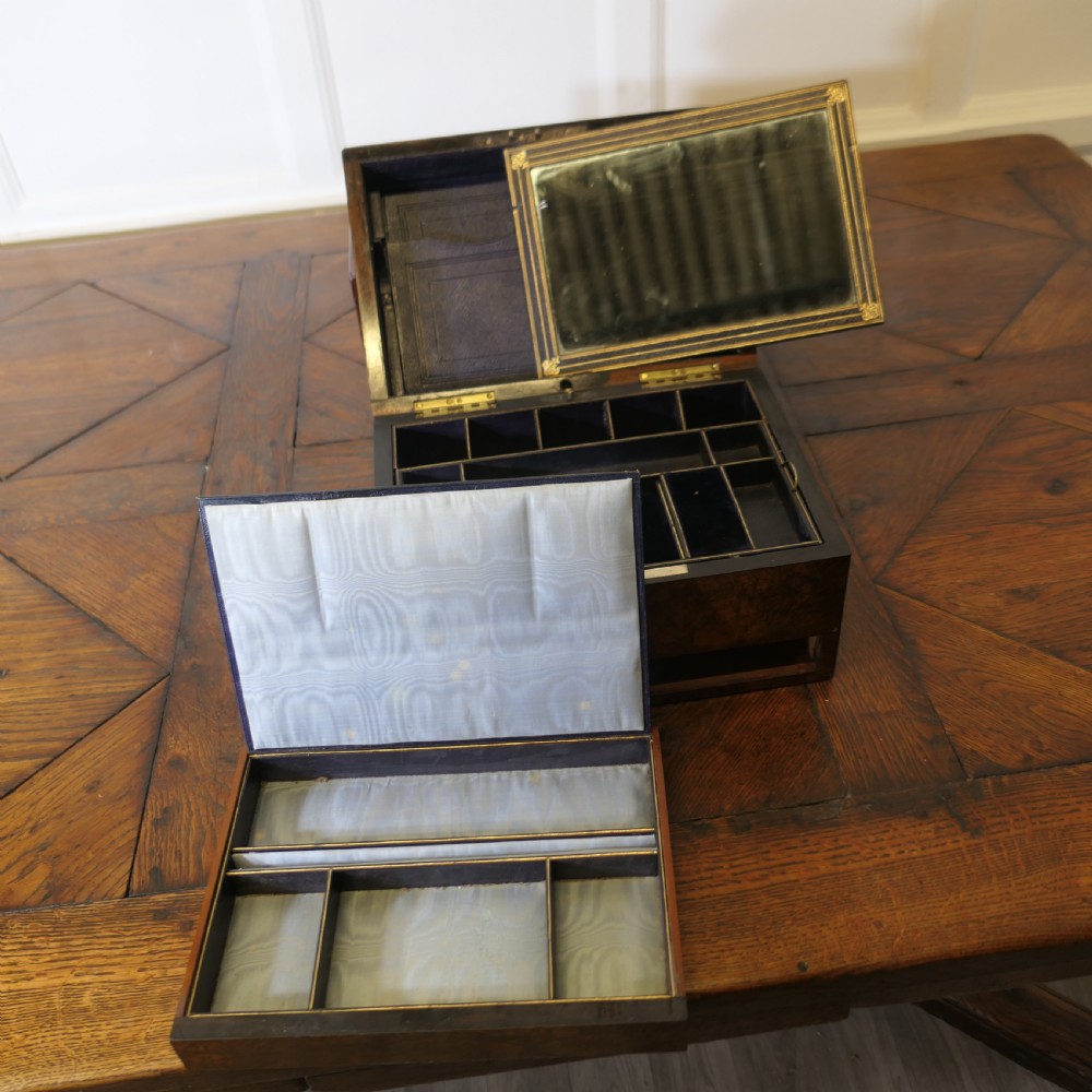 A set of three polished antique burr walnut storage boxes featuring brass keyhole escutcheons resting on a parquet floor. View X