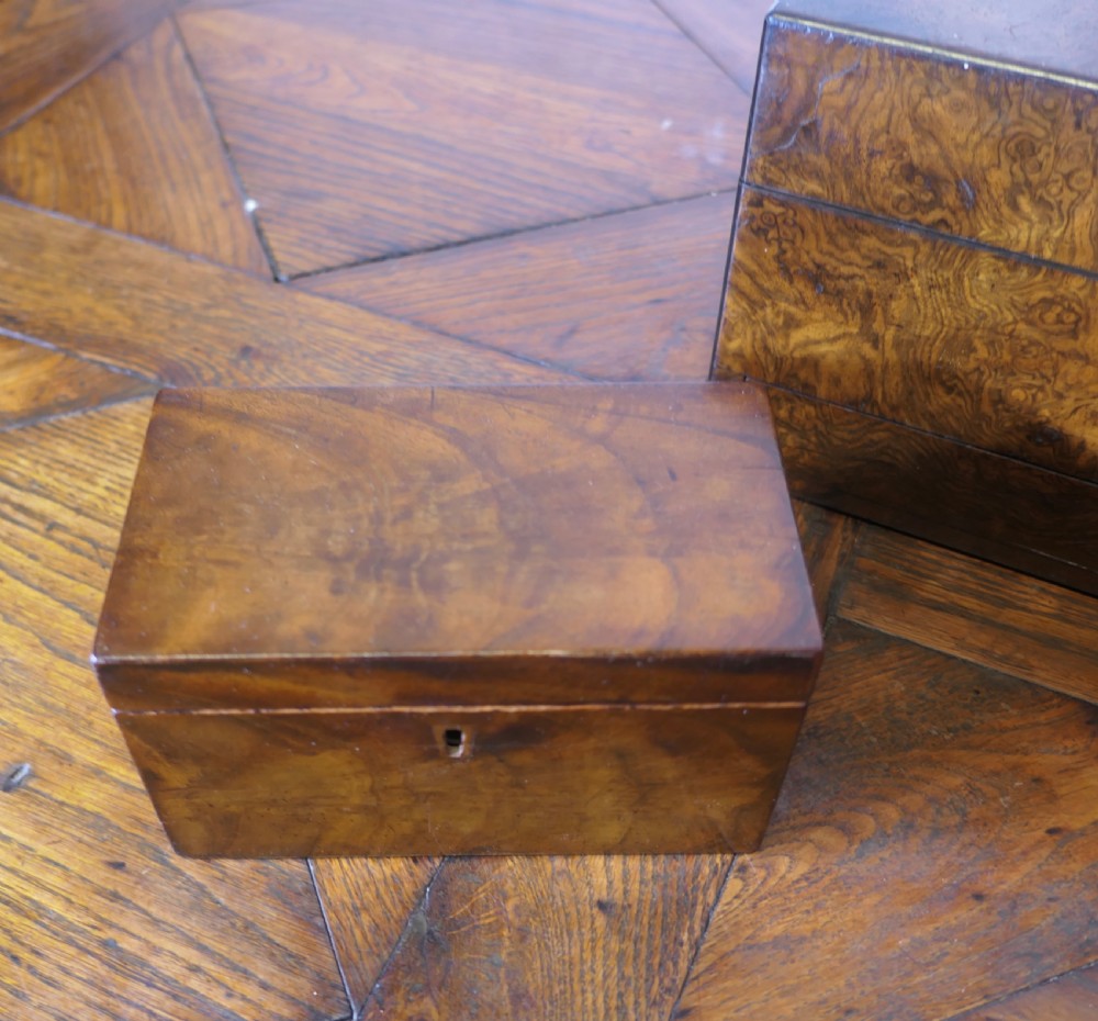 A set of three polished antique burr walnut storage boxes featuring brass keyhole escutcheons resting on a parquet floor. View XII