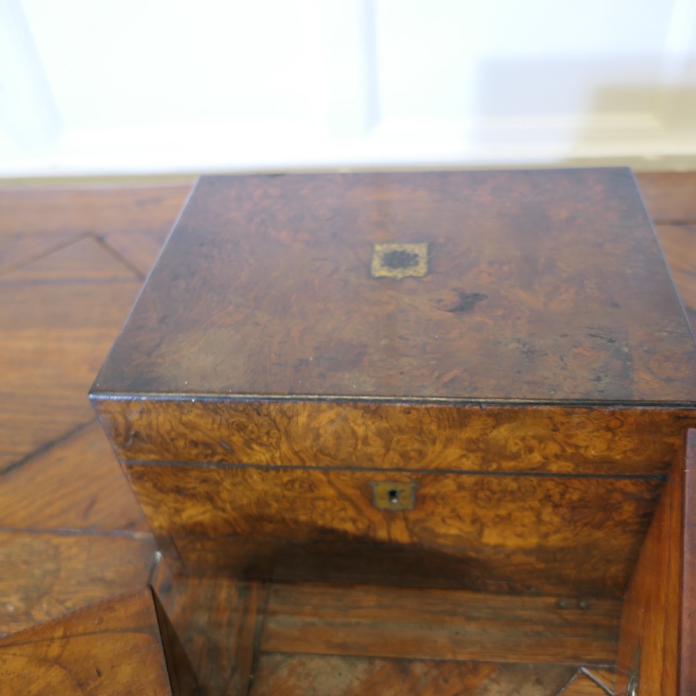 A set of three polished antique burr walnut storage boxes featuring brass keyhole escutcheons resting on a parquet floor. View XIII