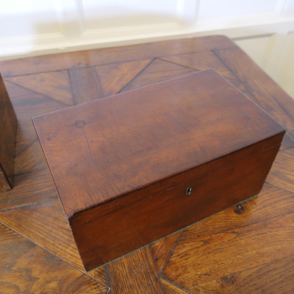A set of three polished antique burr walnut storage boxes featuring brass keyhole escutcheons resting on a parquet floor. View XV