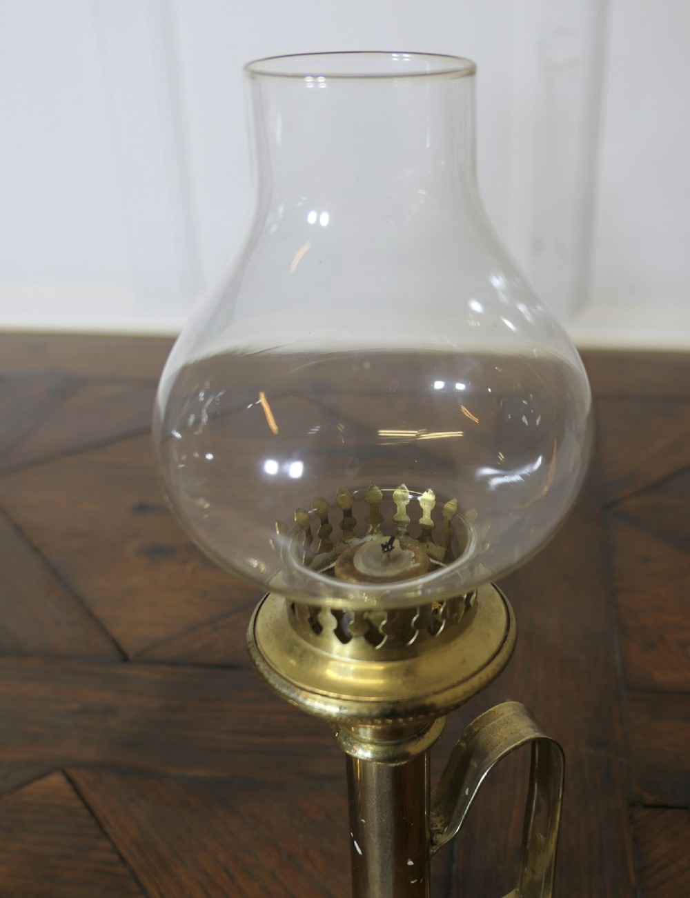 A pair of polished brass candlesticks featuring side handles and removable clear glass hurricane chimneys enclosing lit candles. View VII