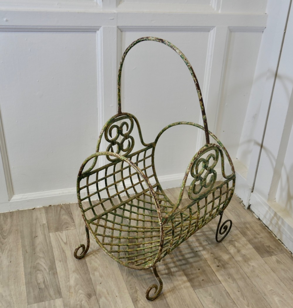 A 19th-century French distressed green painted wrought iron wirework log carrier featuring scroll feet, an elevated loop handle, and open mesh grid sides. View II