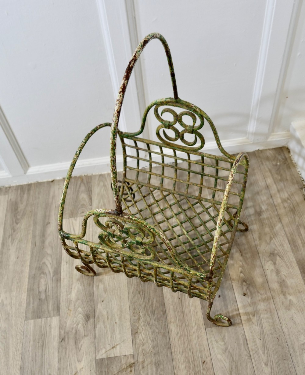 A 19th-century French distressed green painted wrought iron wirework log carrier featuring scroll feet, an elevated loop handle, and open mesh grid sides. View III