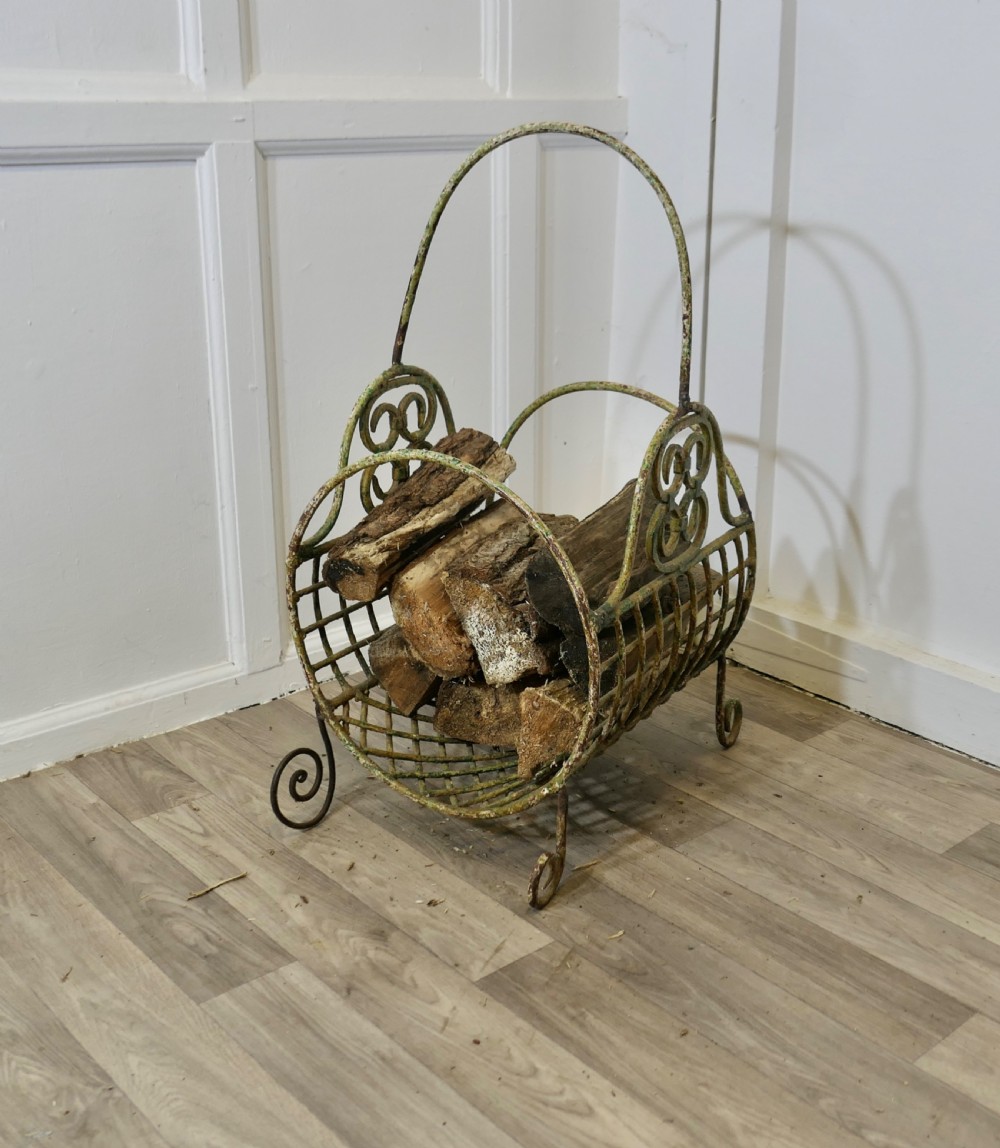 A 19th-century French distressed green painted wrought iron wirework log carrier featuring scroll feet, an elevated loop handle, and open mesh grid sides. View VI