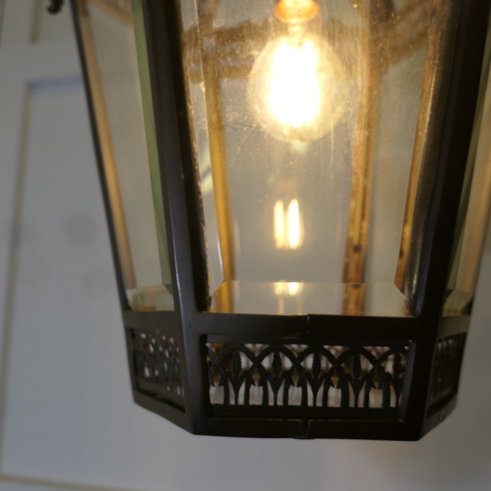 A dark patinated copper hexagonal ceiling lantern with glazed glass panels, scrolled metal supports, and cast Green Man mask decorations. View VIII