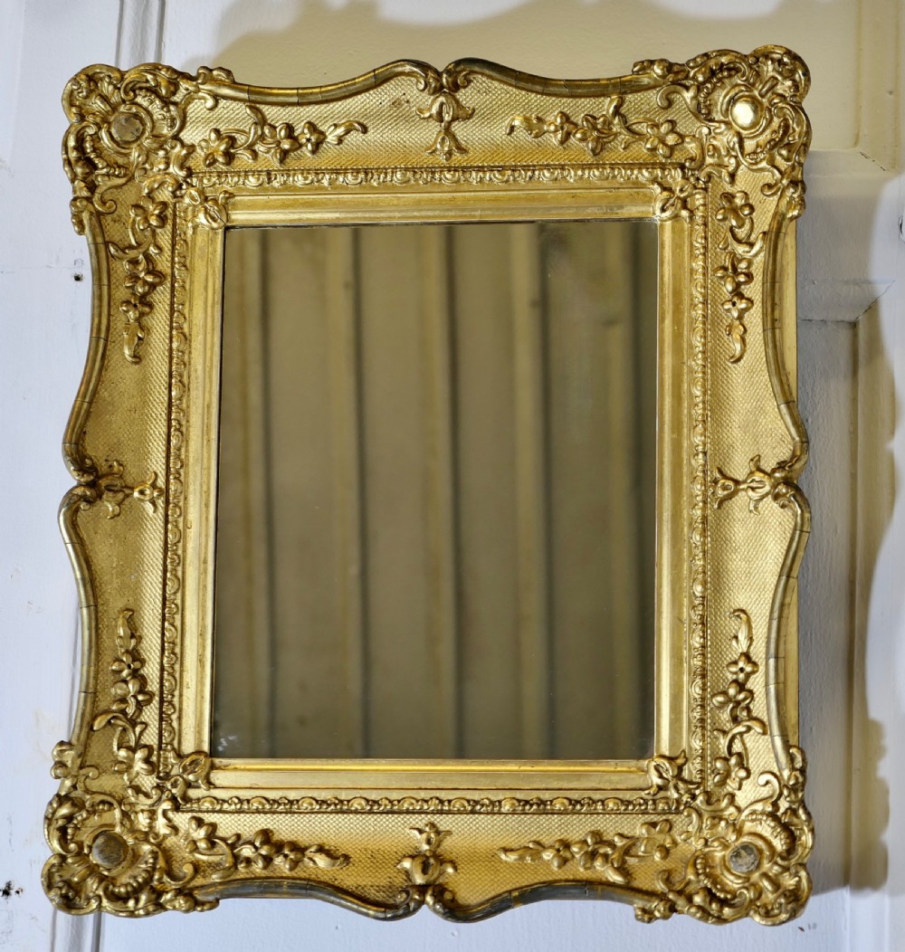 A nineteenth-century French rectangular wall mirror featuring an ornate giltwood frame with floral mouldings and a textured cross-hatched ground. View IV