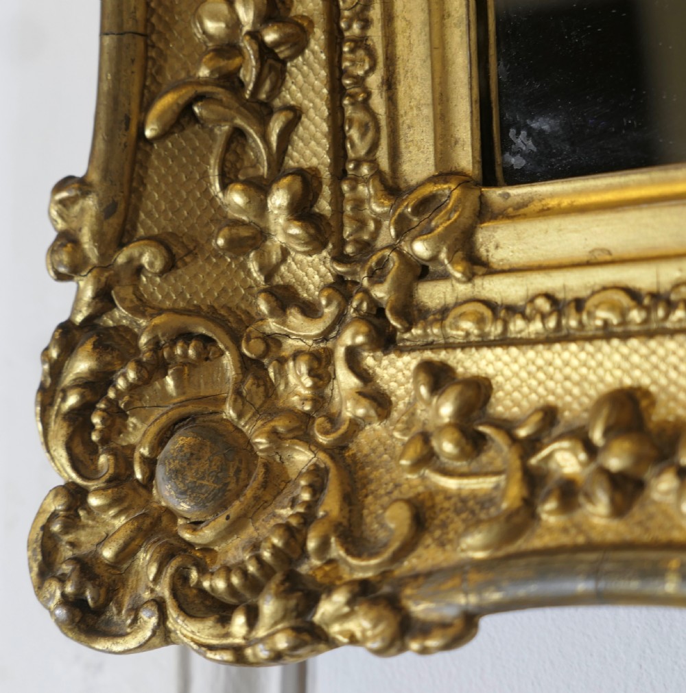 A nineteenth-century French rectangular wall mirror featuring an ornate giltwood frame with floral mouldings and a textured cross-hatched ground. View V
