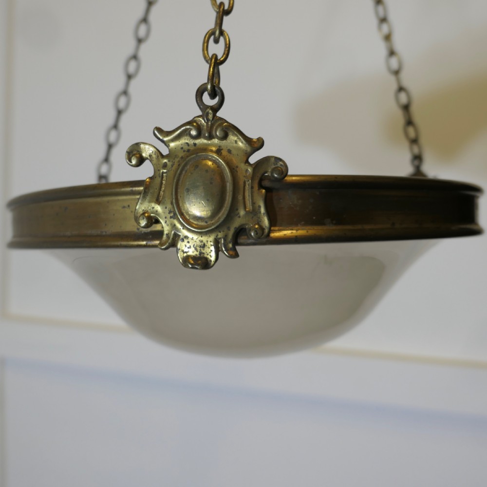 An antique Arts and Crafts ceiling light featuring a bowl-shaped opalescent glass shade suspended by three brass chains attached to a brass collar and ceiling rose. View III