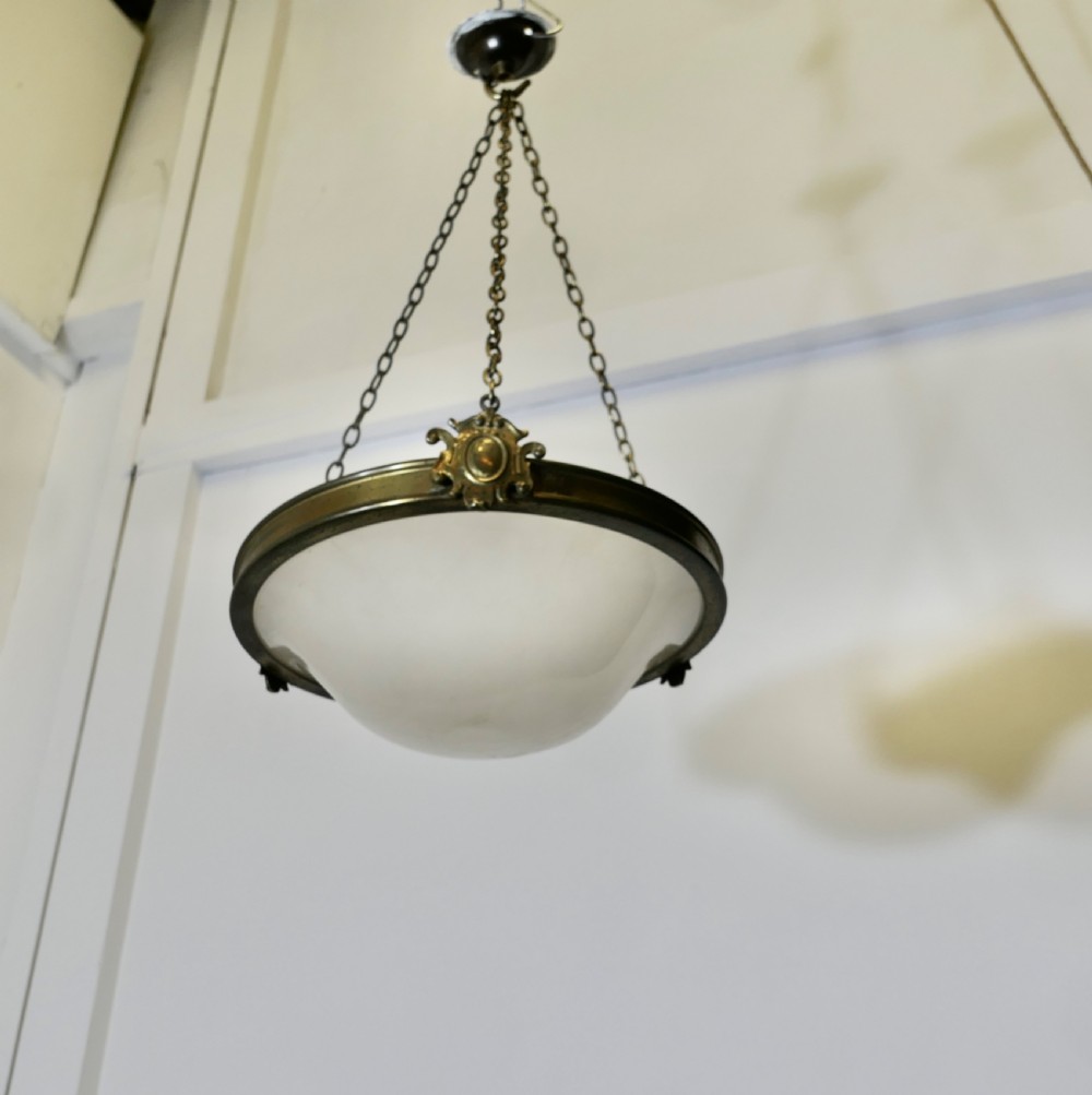 An antique Arts and Crafts ceiling light featuring a bowl-shaped opalescent glass shade suspended by three brass chains attached to a brass collar and ceiling rose. View VI