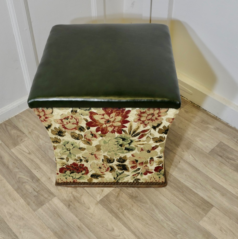 A waisted upholstered ottoman featuring a dark green leather seat above floral woven tapestry sides. View II
