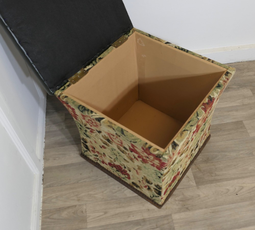A waisted upholstered ottoman featuring a dark green leather seat above floral woven tapestry sides. View V