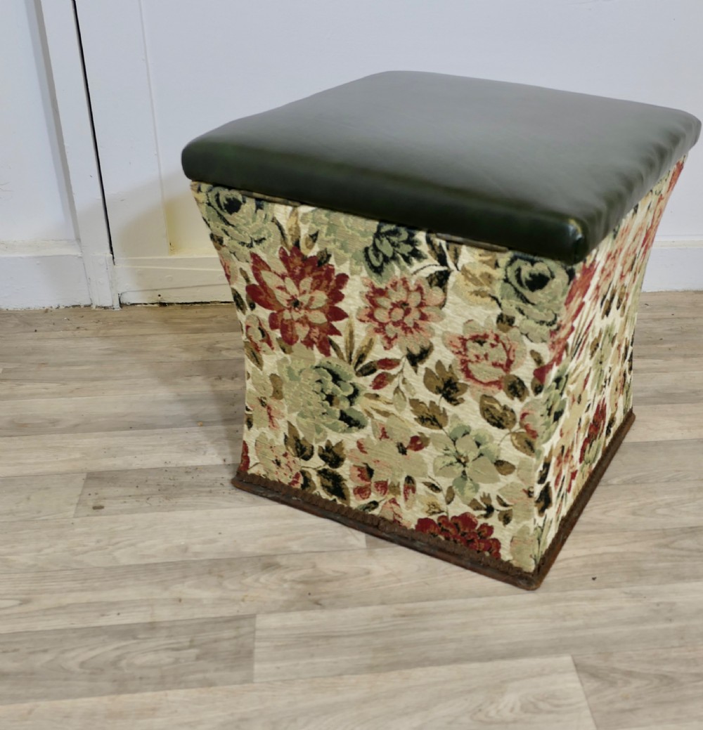 A waisted upholstered ottoman featuring a dark green leather seat above floral woven tapestry sides. View VI