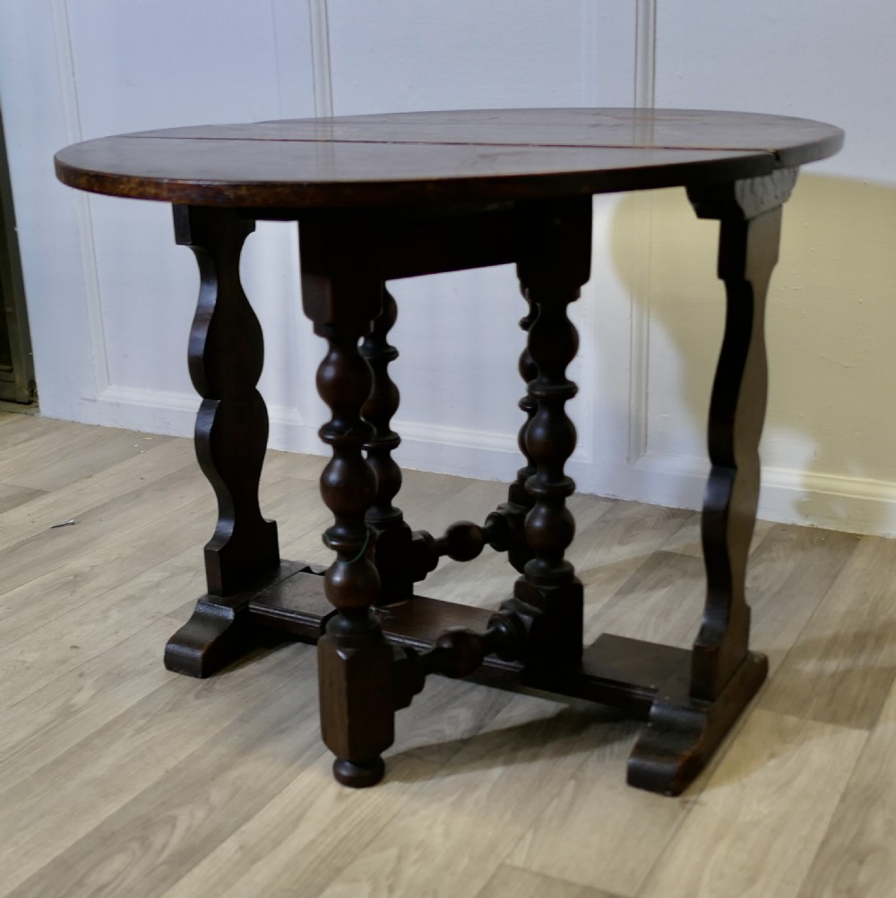 A dark oak low occasional coffee table with two drop-leaf flaps, turned bobbin legs, and a stretcher base. View II