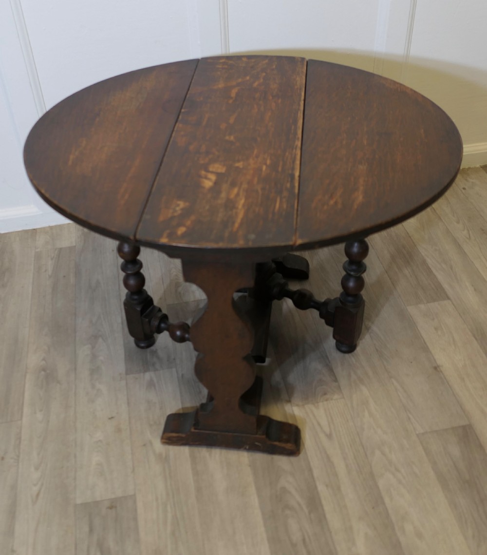 A dark oak low occasional coffee table with two drop-leaf flaps, turned bobbin legs, and a stretcher base. View V
