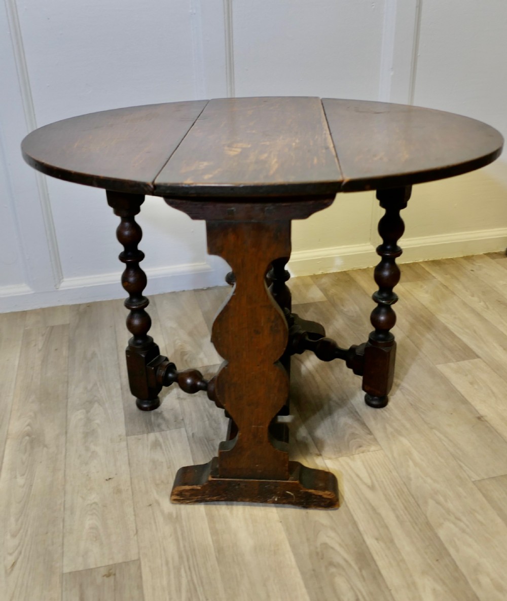 A dark oak low occasional coffee table with two drop-leaf flaps, turned bobbin legs, and a stretcher base. View VI