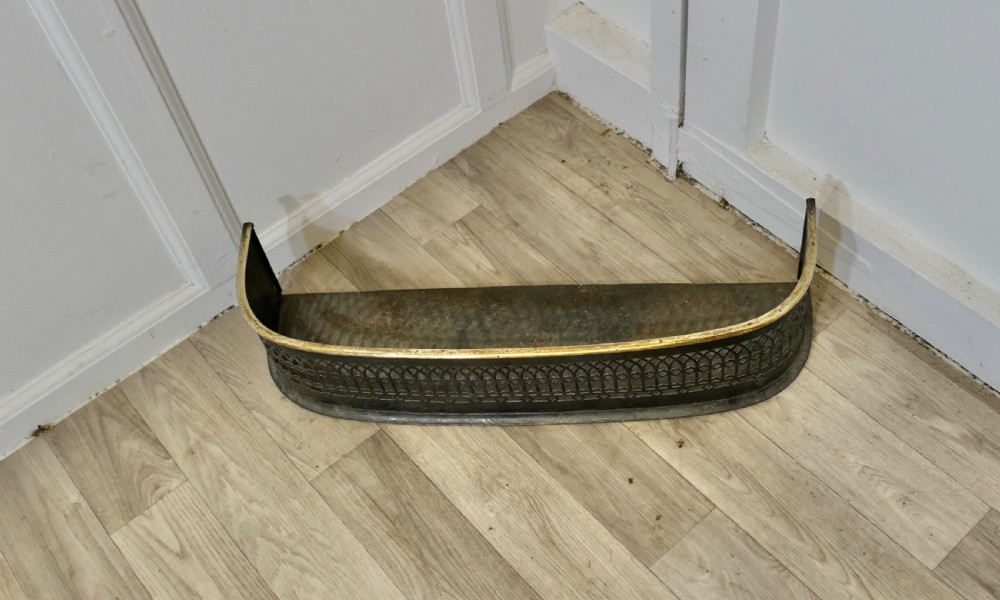A Victorian curved fireplace fender featuring black pierced lattice ironwork topped with a polished brass rim. View III