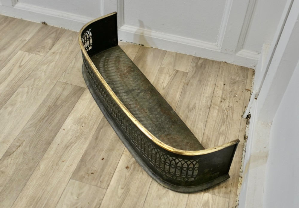 A Victorian curved fireplace fender featuring black pierced lattice ironwork topped with a polished brass rim. View IV