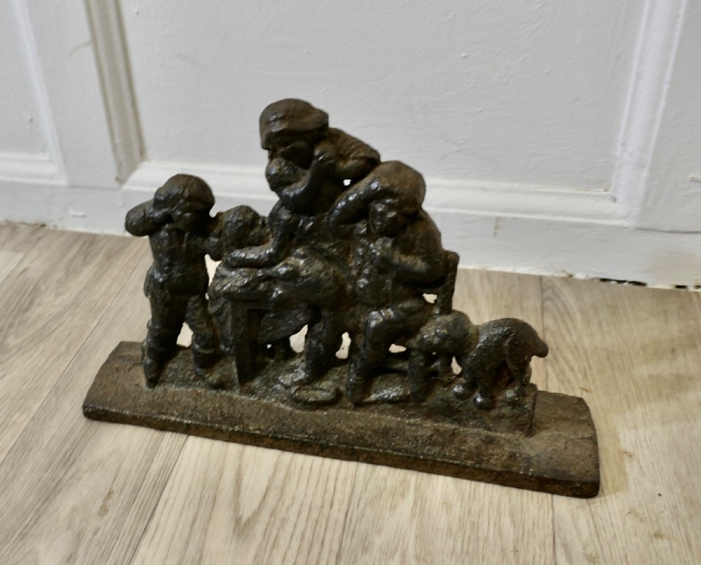 A 19th-century dark cast iron doorstop featuring a figurative narrative scene mounted on a flat rectangular plinth base. View III