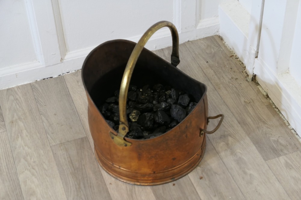 An Arts and Crafts beaten copper helmet coal scuttle featuring a brass overhead swing handle and a small rear tipping handle. View III