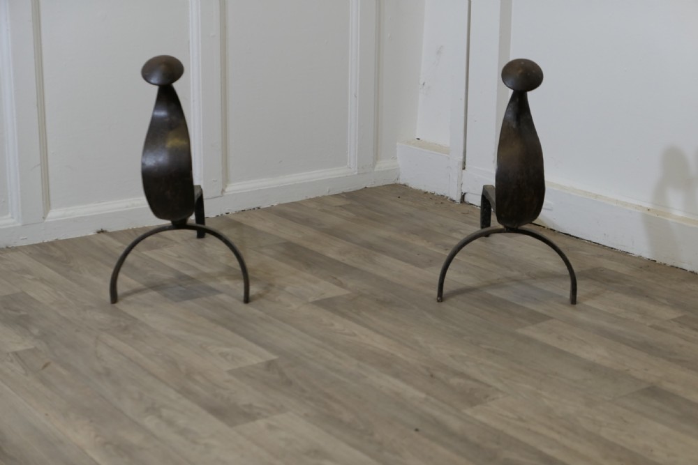 A pair of dark wrought iron French Gothic fire dogs featuring arched legs, curved upright front plates, and disc finials.