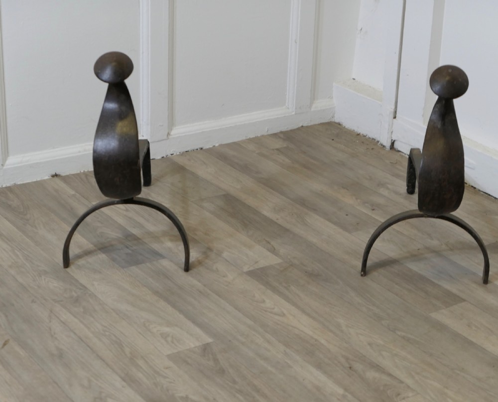 A pair of dark wrought iron French Gothic fire dogs featuring arched legs, curved upright front plates, and disc finials. View II