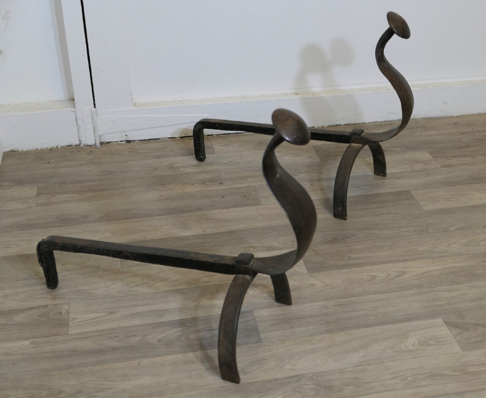 A pair of dark wrought iron French Gothic fire dogs featuring arched legs, curved upright front plates, and disc finials. View V