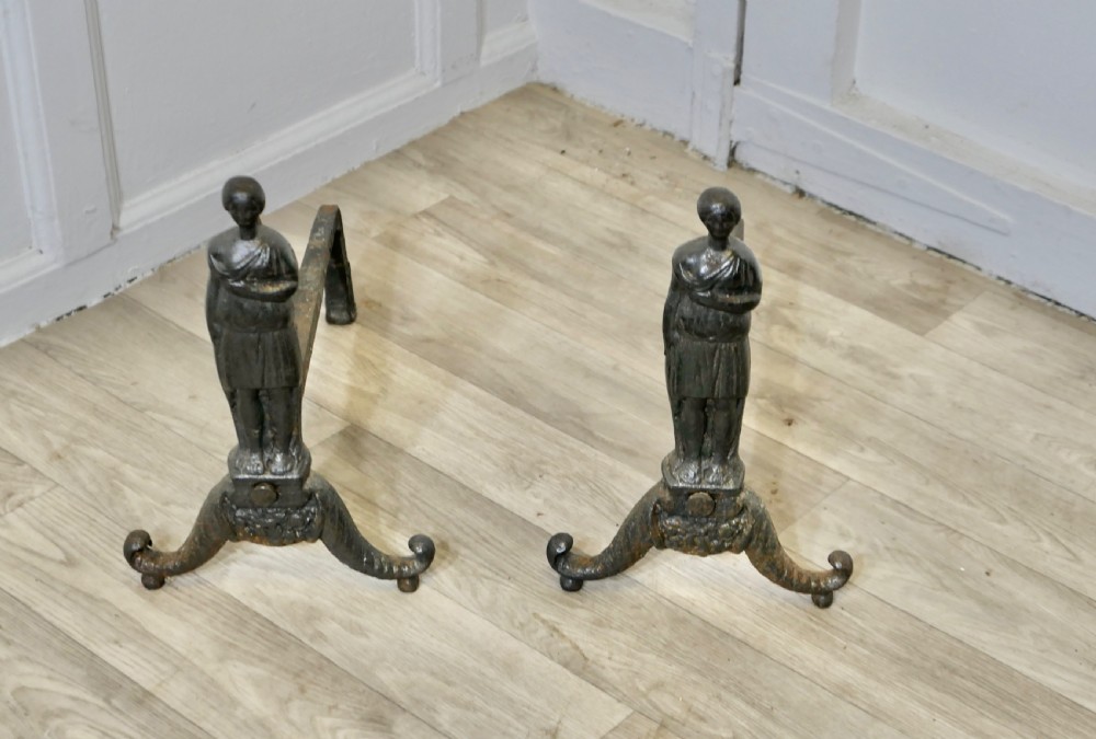A pair of dark cast iron French Gothic andirons featuring standing guardian figures on scrolled tripod bases. View II