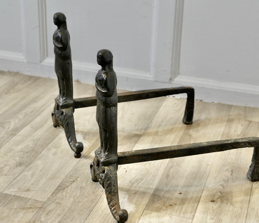 A pair of dark cast iron French Gothic andirons featuring standing guardian figures on scrolled tripod bases. View III