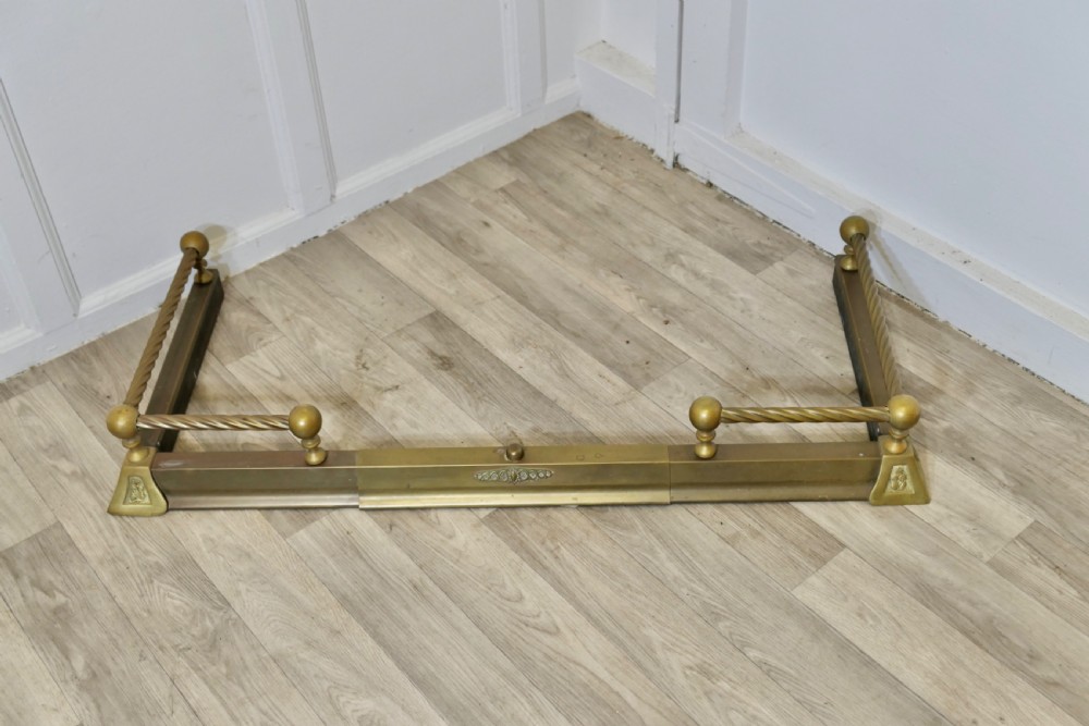 An adjustable Victorian brass fireplace fender featuring barley twist top rails, spherical finials, and central decorative moulding. View VI