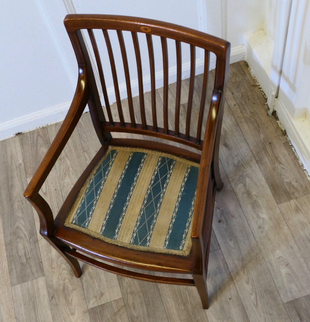 A dark mahogany Regency style childs open armchair with vertical back splats, sweeping armrests, and a striped fabric seat. View II